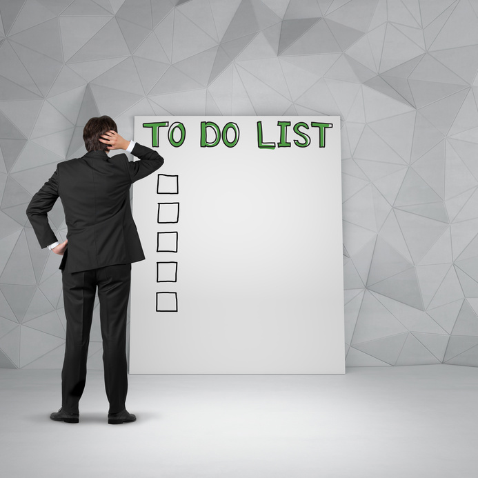 Thinking businessman standing in front of to do list